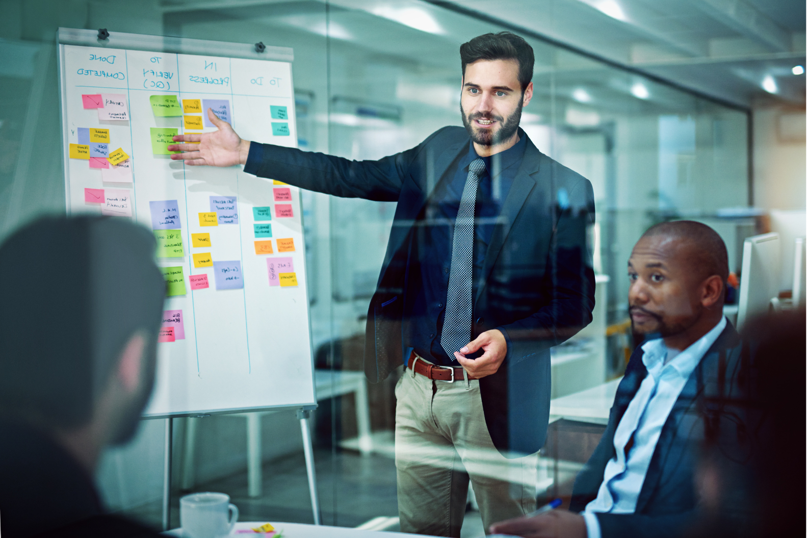 Chico pointing to his whiteboard, deciding with his colleagues all the points of the phases necessary for a successful implementation of the campaign.
